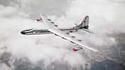 Das Foto zeigt die Convair NB-36H der United States Air Force im Flug über einer geschlossenen Wolkendecke. Das großspannige Propellerflugzeug, eine modifizierte B‑36 für Nuklearforschungszwecke, ist in Schrägaufsicht mit deutlich erkennbaren Triebwerksgondeln und Leitwerk aufgenommen. Laut Dateiname stammt die Aufnahme aus dem Jahr 1955 und zeigt die Maschine im Verband mit einer Boeing B‑50 (USAF).