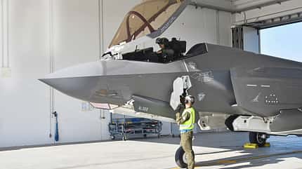 Das Foto zeigt eine Lockheed F-35 in einem Hangar mit geöffneter Cockpithaube. Ein Pilot sitzt im Cockpit, während ein Mitglied der Bodencrew am Bugbereich an einem geöffneten Servicepanel arbeitet; typische Merkmale des Stealth-Mehrzweckkampfflugzeugs wie die graue Radarabdeckung und bündige Paneele sind erkennbar. Der Dateiname weist den Aufnahmeort als Italien aus.
