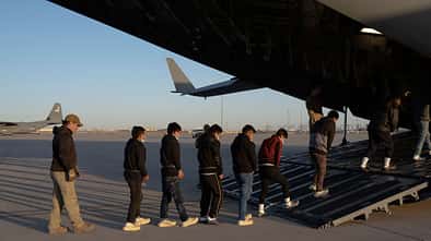 Gefesselte Menschen betreten C-17 der USAF 