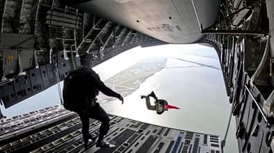 Rettungsschwimmer springen aus C-17-Transporter