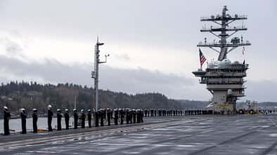 Seeleute umringen das Deck der USS Nimitz beim Auslaufen