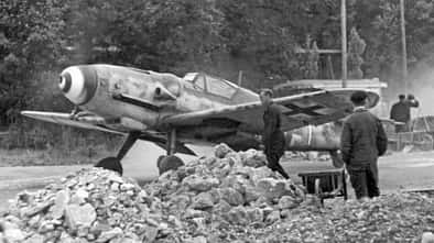 Messerschmitt Bf 109G rollt über eine provisorische Rollbahn, beobachtet von Bodenpersonal