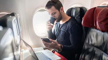 Smartphone Handy Kabine Man working in airplane using cellphone and drinking coffee