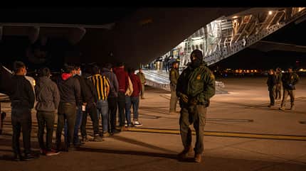 C-17, USAF, Globemaster Vermummter Wachmann beaufsichtigt Einwanderer vor C-17 der USAF