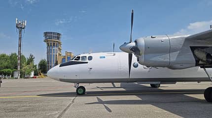 Flugzeug, Propellerflugzeug, Flughafen, Kontrollturm, Rollfeld Ein Propellerflugzeug steht auf dem Rollfeld eines Flughafens. Im Hintergrund ist ein Kontrollturm zu sehen.