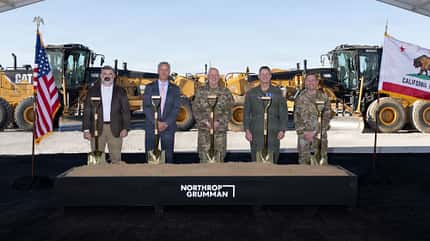 Gruppenbild mit Spaten vor Baumaschinen