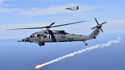 HH-60W feuert Täuschkörper ab mit F-15 im Hintergrund