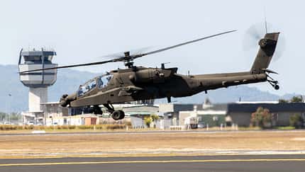 AH-64 Apache Hubschrauber im Schwebeflug vor Kontrollturm