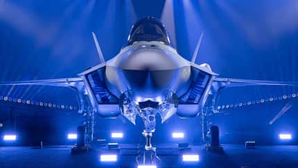 F-35, Lockheed Martin, Finnland Eine F-35 auf einer Bühne wird mit blauem Licht angestrahlt.