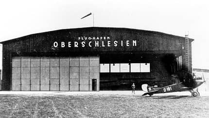 Drehkreuz Gleiwitz, Flugplatz Gleiwitz, Oberschlesische Luftverkehrs AG, Schlesien, Danzig, Oberschlesien, Junkers, Aerolot, DLH, Dreiländerecke, Luftverkehrsnetz Eine LVG B III (D 181) des Meteorologischen Observatorium Breslau-Krietern vor einer Gleiwitzer Halle