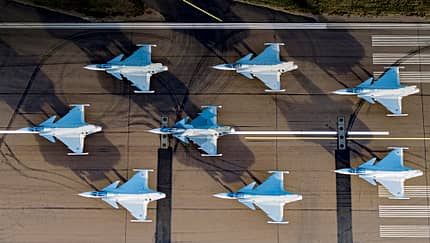 Sieben Saab Gripen E/F stehen auf einer Startbahn, von oben fotografiert