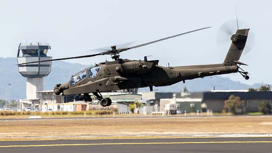 AH-64 Apache Hubschrauber im Schwebeflug vor Kontrollturm