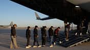 Gefesselte Menschen betreten C-17 der USAF 