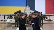 Rafale, Ukraine, Frankreich Der französische und ukrainische Präsident schütteln sich die Hände. Im Hintergrund ist ein Rafale-Kampfjet zu sehen.